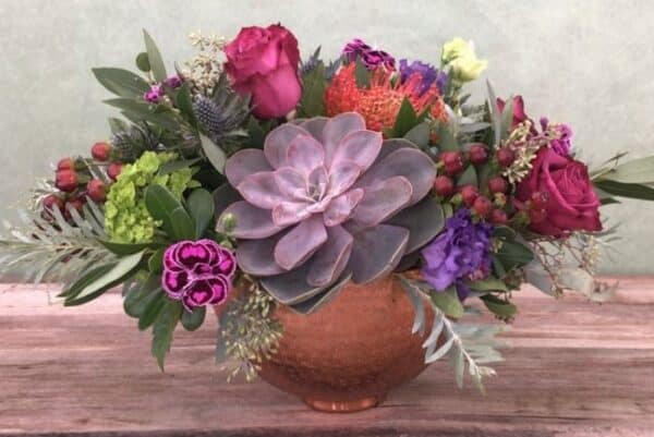 Copper Moon is a bright flower arrangement featuring hydrangea and roses with a succulent in a copper bowl