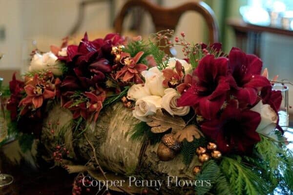 Copper Penny Flowers holiday birch log filled with flowers and evergreens