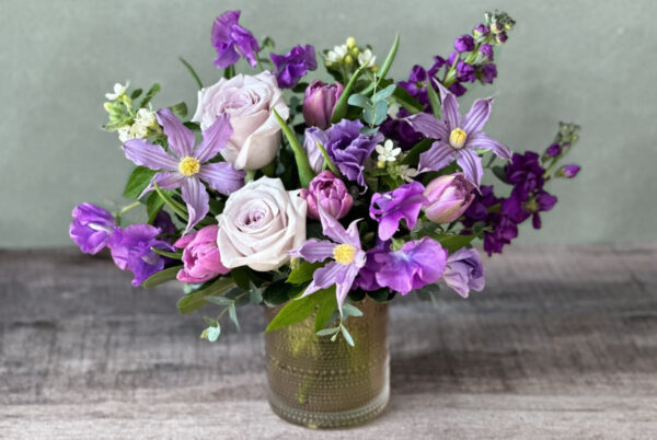 Meg's Frolic is a lavender and purple flower arrangement in a glass vase